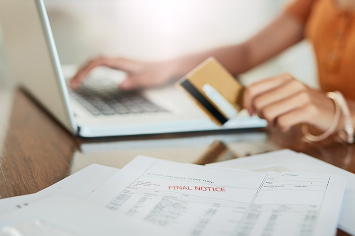 Person Holding Credit Card next to Laptop